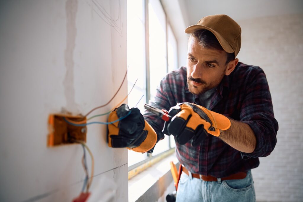 Professional electrician working at renovating home.